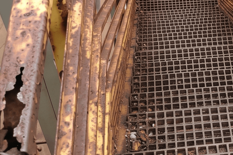 Escada industrial metálica com guarda-corpo e piso corroídos